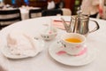 Tea service on a white table : Iron kettle, tea cup with hot tea, a soup bowl