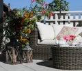 Tea-set and beautiful flowers on sunny terrace. A rattan patio set including a sofa. Royalty Free Stock Photo