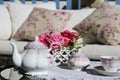 Tea-set and beautiful flowers on sunny terrace. A rattan patio set including a sofa. Royalty Free Stock Photo