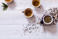 Tea set cups, teapot and brewed tea with dried leaves on white wooden table, green black herbal homemade hot beverage in porcelain Royalty Free Stock Photo