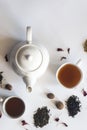 Tea set with white ceramic tea pot, dried rose flowers and other tea ingredients on the white. Flat lay view of various dried teas Royalty Free Stock Photo