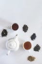 Tea set with white ceramic tea pot and other tea ingredients on the white. Flat lay view of various dried teas and teapot. View Royalty Free Stock Photo