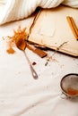 Tea spoon with spilled cocoa powder on linen background with old-fashioned cookbooks aside