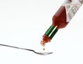 Tea Spoon with Tabasco, Hot Pepper Sauce, Bottle against White Background Royalty Free Stock Photo