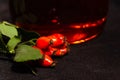 Tea and a sprig of fresh ripe rosehip berries on a black background. Closeup. Copy space