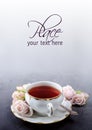 Tea time banner with vintage white porcelain tea cup, gentle pink roses on a dark gray background Royalty Free Stock Photo