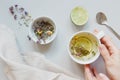 Tea time. Hands holding cup of hot tea. Dry herbal tea, lime and spoon on the gray background, top view Royalty Free Stock Photo