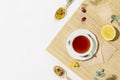 Cup of herbal tea with lemon and dry flowers on wooden napkin with copy space