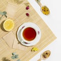 Cup of herbal tea with lemon and dry flowers on wooden napkin