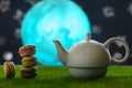 Tea time, oriental tales, teapot with French sweets, macaroons, starry sky and moon. Delicious and spicy tea with sweets, close-up
