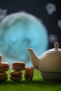 Tea time, oriental tales, teapot with french sweets macaroons, starry sky and moon. Delicious and spicy tea with sweets, vertical