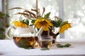 Tea in a transparent teapot and sunflowers in a ceramic vase