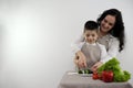 Bonding Concept. Cheerful mother helping her son to cook, teaching little boy how to prepare healthy vegetable salad