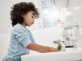 Teach kids to regularly wash their hands. an adorable little boy washing his hands at a tap in a bathroom at home. Royalty Free Stock Photo