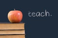 Teach written on blackboard with apple and books Royalty Free Stock Photo