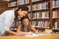 Teacher assisting girl with homework in library Royalty Free Stock Photo