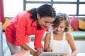 Teacher assisting girl using digital tablet in library Royalty Free Stock Photo