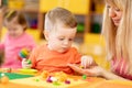 Teacher with babies in creche. Kids on lesson in kindergarten