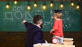 Teacher with beard, father teaches little son in classroom, chalkboard on background. Boy, child in graduate cap looks Royalty Free Stock Photo