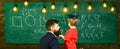 Teacher with beard, father teaches little son in classroom, chalkboard on background. Boy, child in graduate cap Royalty Free Stock Photo