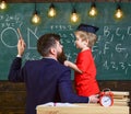 Teacher with beard, father teaches little son in classroom, chalkboard on background. Instructive conversation concept