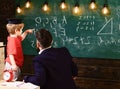 Teacher with beard, father teaches little son in classroom, chalkboard on background. Prodigy child concept. Boy, child