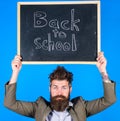 Teacher bearded man holds blackboard with inscription back to school blue background. Teacher with tousled hair