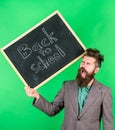 Teacher bearded man holds blackboard with inscription back to school green background. Teacher with tousled hair