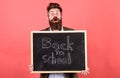 Teacher bearded man holds blackboard with inscription back to school red background. Teacher with tousled hair stressful