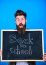 Teacher bearded man stands and holds blackboard with inscription back to school blue background. Continue your education
