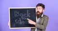 Teacher bearded man stands and holds blackboard with inscription back to school violet background. Continue your