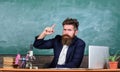 Teacher bearded man tell interesting story. Teacher charismatic hipster sit table classroom chalkboard background