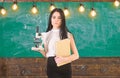 Teacher of biology holds book and microscope. Biology concept. Lady scientist holds book and microscope, chalkboard on