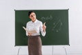 Teacher with book and chalk pointing Royalty Free Stock Photo