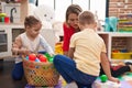 Teacher with boy and girl playing with balls sitting on floor at kindergarten Royalty Free Stock Photo
