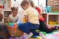 Teacher with boy and girl playing with balls sitting on floor at kindergarten Royalty Free Stock Photo