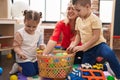 Teacher with boy and girl playing with balls sitting on floor at kindergarten Royalty Free Stock Photo