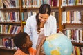 Teacher and boy looking at globe in library Royalty Free Stock Photo