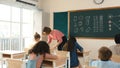 Teacher checking cute student homework while explaining idea at class. Pedagogy.