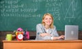 Teacher cheerful pleasant woman educator sit table classroom work with laptop. Teacher happy work in school chalkboard