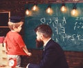 Teacher and child talking in the classroom. Little schoolboy in Oxford cap answering the question in front of the green Royalty Free Stock Photo