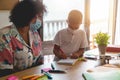 Teacher and child wearing protective face masks in classroom during coronavirus outbreak - Soft focus on kid face Royalty Free Stock Photo