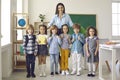 Portrait of happy teacher and little group of elementary students on first day at school