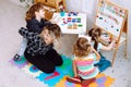 Teacher with children having fun and playing games, learning letters and numbers in kid development childcare center Royalty Free Stock Photo