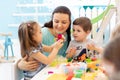 Teacher with children working with plasticine at kindergarten or playschool