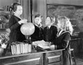 Teacher in a classroom with three pupils pointing to a globe Royalty Free Stock Photo