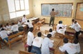 Teacher in classroom writing on blackboard