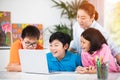 Teacher and Cute Asian children using laptop computer together. Royalty Free Stock Photo