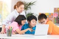 Teacher and Cute Asian children using laptop computer together. Royalty Free Stock Photo