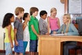 Teacher at desk, students and education with learning for growth and development in classroom. Woman, children and Royalty Free Stock Photo